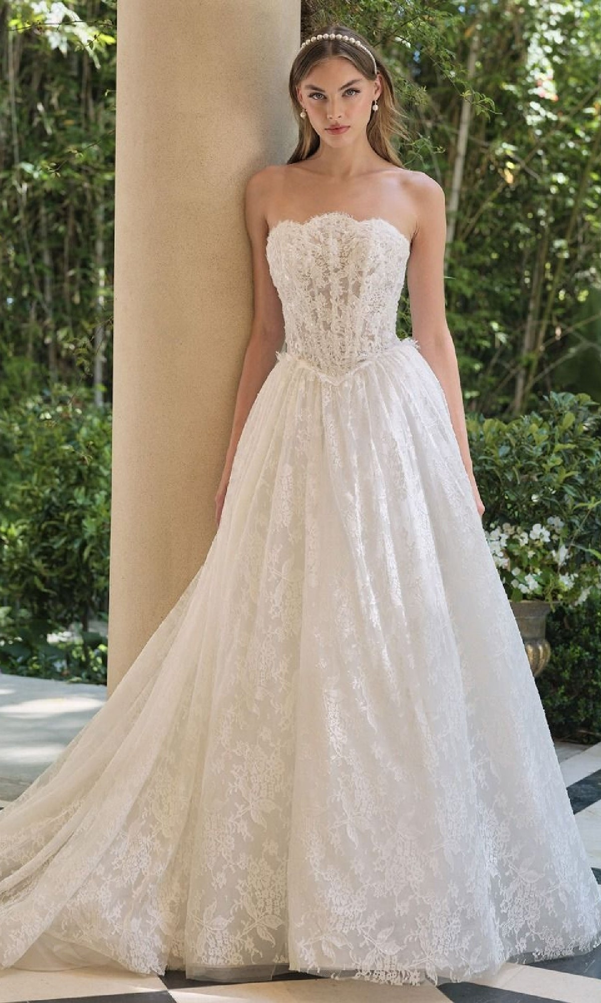 Woman wearing a strapless lace wedding dress in an outdoor setting.